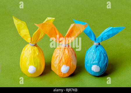 Three colorful Easter eggs in the form of Easter rabbits on a bright green background Stock Photo