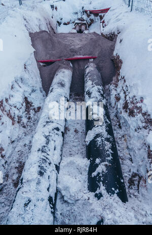 Two big pipes in the trench covered lightly with some snow on a winter day at a construction site Stock Photo