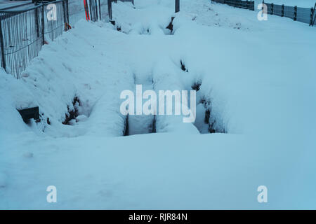 Two big pipes in the trench covered with some snow on a winter day at a construction site Stock Photo