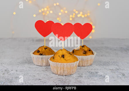 Three tasty cupcakes with big red hearts on light background. Template mockup to celebrate Valentine's day, Mother's' day and Birthday Stock Photo
