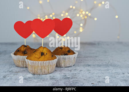 Three tasty cupcakes with big red hearts on light background. Template mockup to celebrate Valentine's day, Mother's' day and Birthday Stock Photo