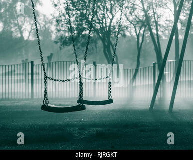 Swings in public park on a misty morning. UK Stock Photo