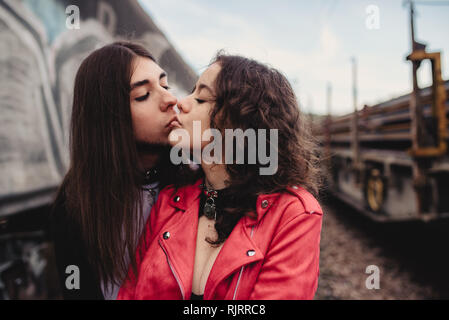 Long haired man hugging and kissing Woman near train Stock Photo