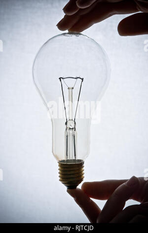 Light bulb held with hands on the white background Stock Photo