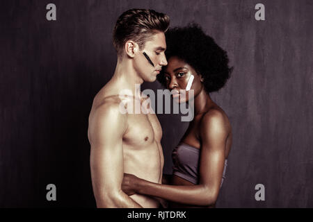 Nice pleasant couple standing against dark background Stock Photo