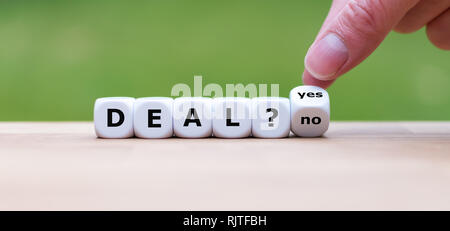 Deal or no deal? Hand turns a dice and changes the word 'no' to 'yes'. Stock Photo