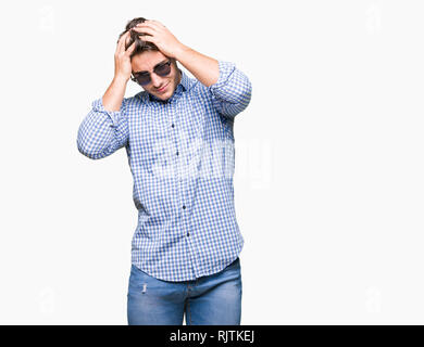 Young handsome man wearing sunglasses over isolated background suffering from headache desperate and stressed because pain and migraine. Hands on head Stock Photo