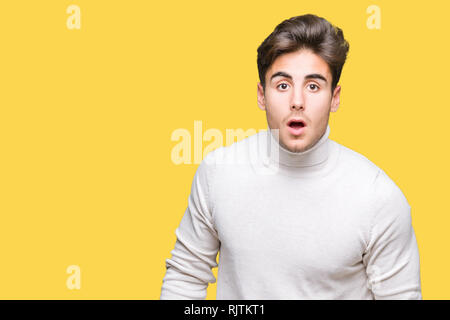 Young handsome man wearing turtleneck sweater over isolated background afraid and shocked with surprise expression, fear and excited face. Stock Photo