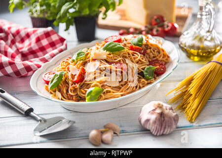 Italian pasta spaghetti bolognese in white bowl with tomatoes parmesan cheese and basil Stock Photo