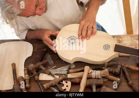 Luthier working on the creation of a stringed instrument. Various tools and instrument are placed on the workbench Stock Photo