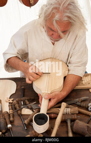 Luthier working on the creation of a stringed instrument. Various tools and instrument are placed on the workbench Stock Photo