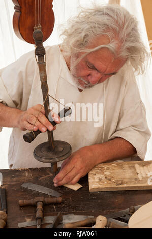 Luthier working on the creation of a stringed instrument. He uses an old manual drill Stock Photo