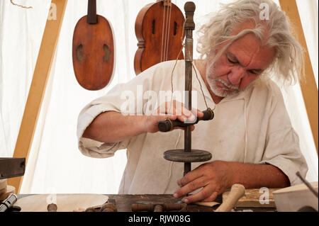 Luthier working on the creation of a stringed instrument. He uses an old manual drill Stock Photo