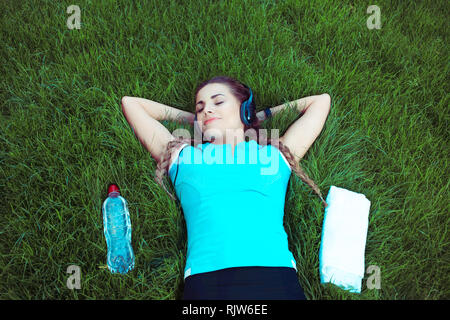 Relaxing fit woman lying on meadow Stock Photo
