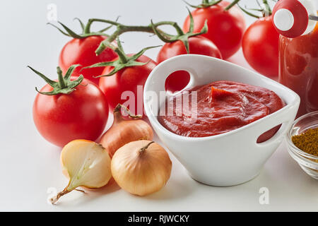 Fresh homemade tomato sauce in a bowl surrounded with ingredients in a close up wide angle view Stock Photo
