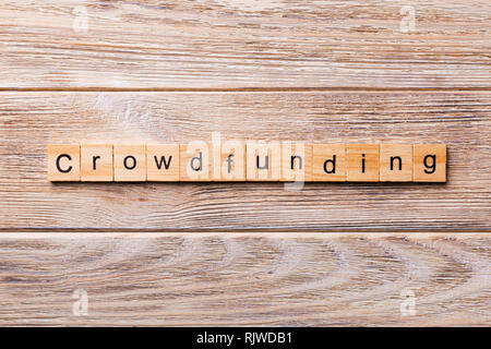 CROWDFUNDING word written on wood block. CROWDFUNDING text on wooden table for your desing, concept. Stock Photo