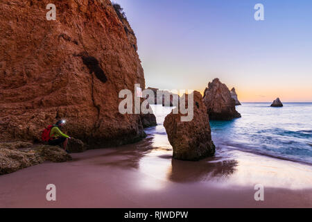 Man sitting by cliff with illuminated headlamp, Alvor, Algarve, Portugal, Europe Stock Photo