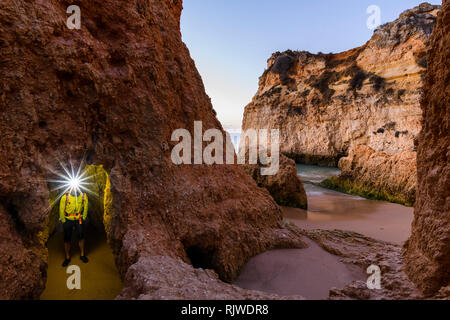 Man standing by cliff with illuminated headlamp, Alvor, Algarve, Portugal, Europe Stock Photo