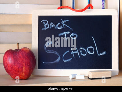 'Back to School' phrase written on a wooden chalkboard using white chalk. Stock Photo