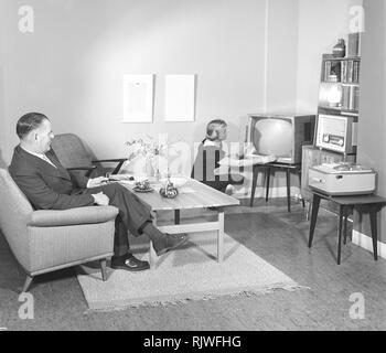 Television in the 1950s. A proud elderly man is pictured in his home with his wife with the latest in electronic home equipment visible. A typical television set on thin legs, a radio and a tape recorder.  Photo Kristoffersson ref CD88-12. Sweden 1959 Stock Photo