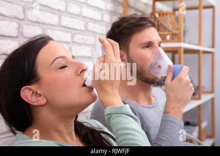 Close-up Of Couple Suffering Asthma Using Inhaler At Home Stock Photo