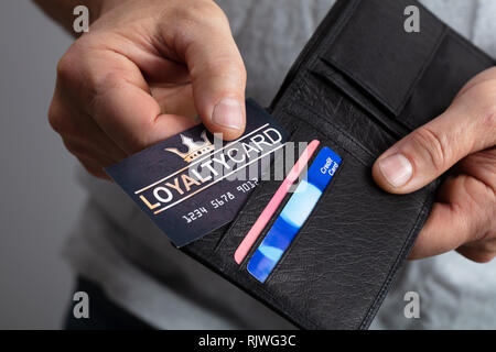 Close-up Of A Person's Hand Removing Black Loyalty Card From Wallet Stock Photo