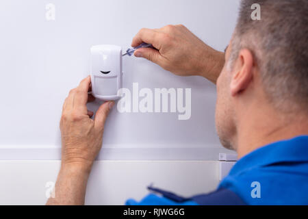 Close-up Of Male Electrician Installing Security System Door Sensor On Wall Stock Photo
