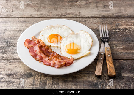 Fried eggs and bacon for breakfast on wooden table. Stock Photo