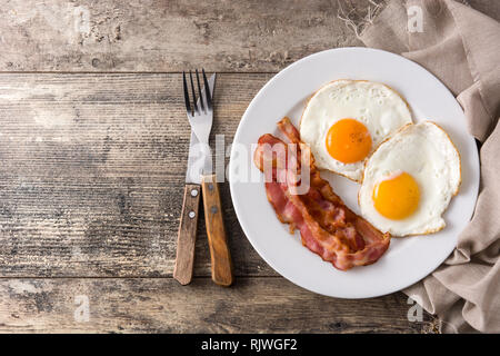 Fried eggs and bacon for breakfast on wooden table. Top view. Copyspace Stock Photo
