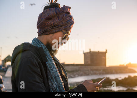 Young Asian Bearded Tourist man with Dreadlocks and scarf on head Having Fun in Essaouira, Morocco at the evening sunset time. Stock Photo