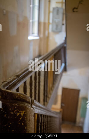 bannister curving round on a staircase leading down to a door Stock Photo