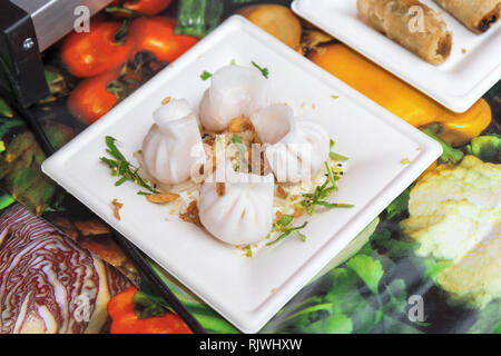 Asian street food, steamed Chinese dumplings, meat and vegetable food, fried onion, traditional asian dumplings served on plastic dish. Demonstration  Stock Photo