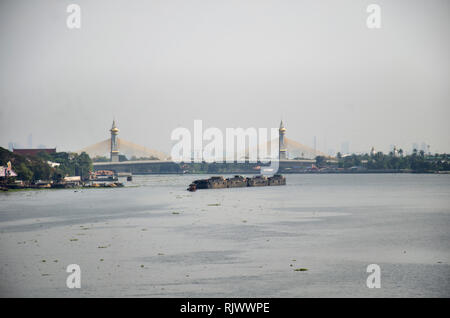 Asian thai people sailing barge and tugboat cargo ship in Chao Phraya or chaopraya river from Bangkok go to Ayutthaya at Phra Nang Klao bridge in Nont Stock Photo