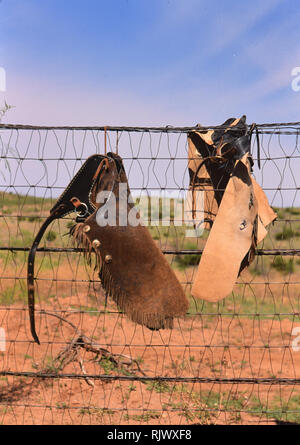 American Cowboys: 1990s Cowboys in the American west, chaps hanging on a fence during spring branding Stock Photo