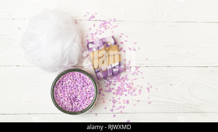 Set for spa treatments. Bath salt a piece of natural soap sponge washcloth stacked on a light background. Flat layout. Stock Photo