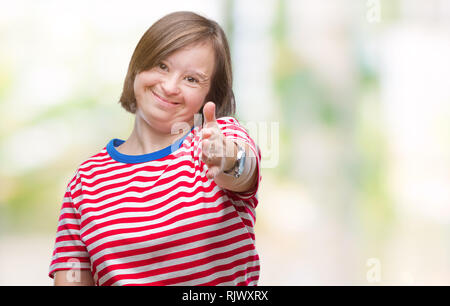 Young adult woman with down syndrome over isolated background smiling friendly offering handshake as greeting and welcoming. Successful business. Stock Photo