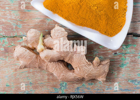 Turmeric powder and ginger root on old wood, top view Stock Photo