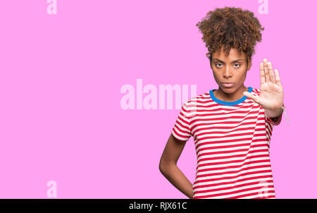 Beautiful young african american woman over isolated background doing stop sing with palm of the hand. Warning expression with negative and serious ge Stock Photo