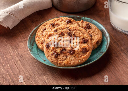 A closeup of chocolate chip cookies with milk on a dark rustic wooden table Stock Photo