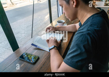 Young male student reading book in a cafe Stock Photo