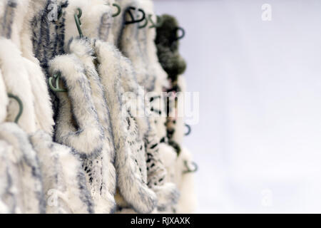 Warm winter animal fur clothes for sale in city street market . Fashion industry, animal rights Stock Photo