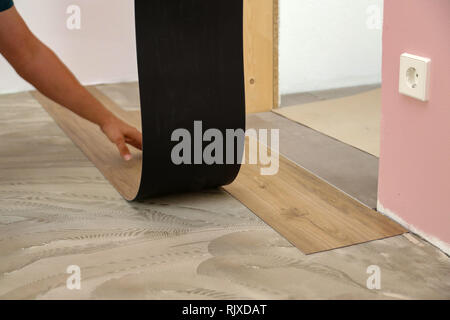 Work on laying flooring. Worker installing new vinyl tile floor. Stock Photo
