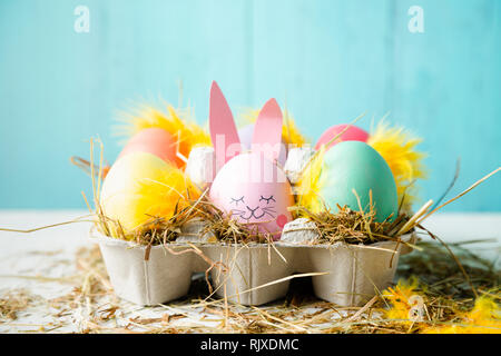 Cute and funny easter eggs with an egg decorated as a rabbit against a turquoise background Stock Photo