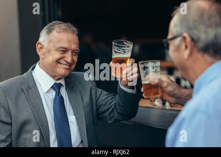 Senior business professionals enjoying a glass of beer at bar after work. businessmen having drinks after work at the bar. Stock Photo