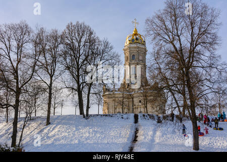 Children ride from the ice slide on a sunny winter day. Winter landscape. Temple of Holy Virgin in Dubrovitsy in the Moscow region, Podolsk Russia Stock Photo