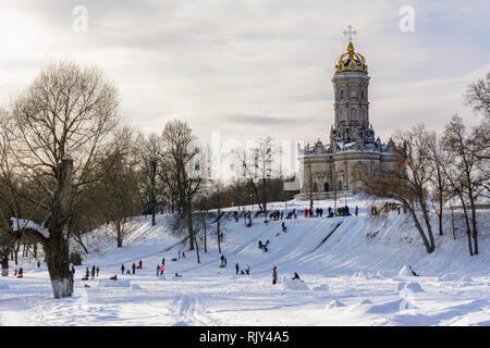 Children ride from the ice slide on a sunny winter day. Winter landscape. Temple of Holy Virgin in Dubrovitsy in the Moscow region, Podolsk Russia Stock Photo