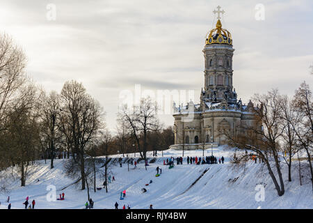 Children ride from the ice slide on a sunny winter day. Winter landscape. Temple of Holy Virgin in Dubrovitsy in the Moscow region, Podolsk Russia Stock Photo