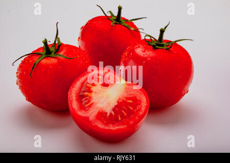 Three wet tomatoes plus one cut open Stock Photo