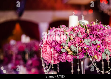 Wedding party table flowers and white candles on the table. Pink pions and wite chrysanthemums bouqet with shining decor. Stock Photo