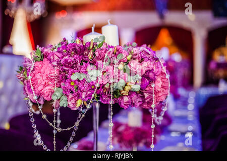 Wedding party table flowers and white candles on the table. Pink pions and wite chrysanthemums bouqet with shining decor. Stock Photo